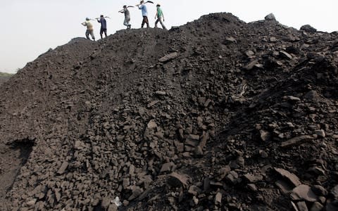 Workers walk on a heap of coal at a stockyard of an underground coal mine in the Mahanadi coal fields at Dera, near Talcher town - Credit: Rupak De Chowdhuri/REUTERS