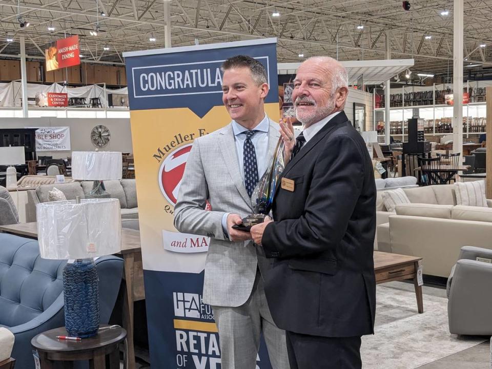 Mark Mueller and Lynwood Mueller hold their Home Furnishings Association Retailer of the Year award.