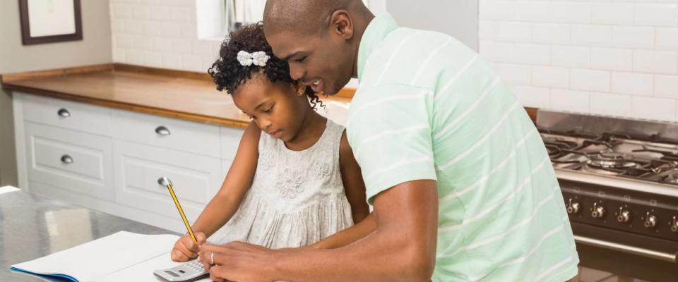 Father helping his daughter with homework in the kitchen