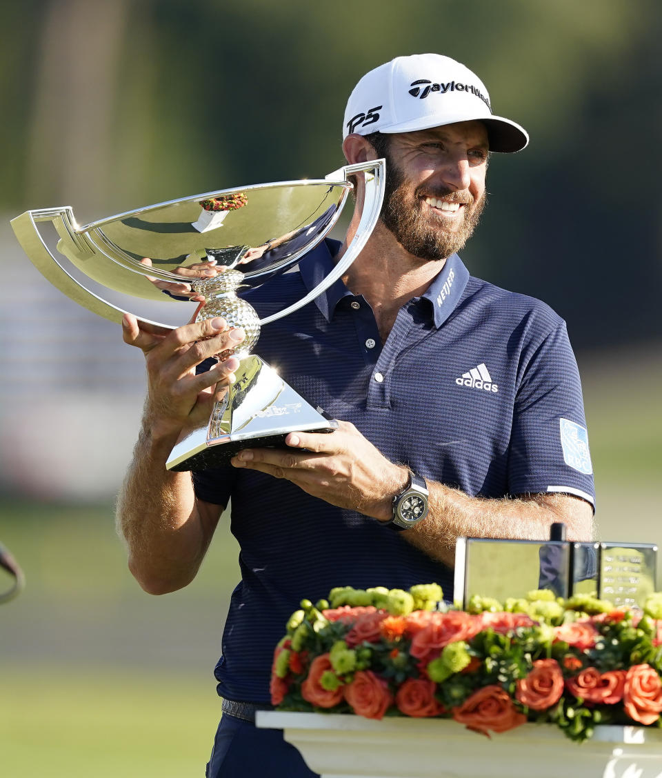 Dustin Johnson holds up the FedEx Cup trophy after winning the Tour Championship golf tournament on Monday, Sept. 7, 2020 at Lake Golf Club in Atlanta. (AP Photo/John Bazemore)