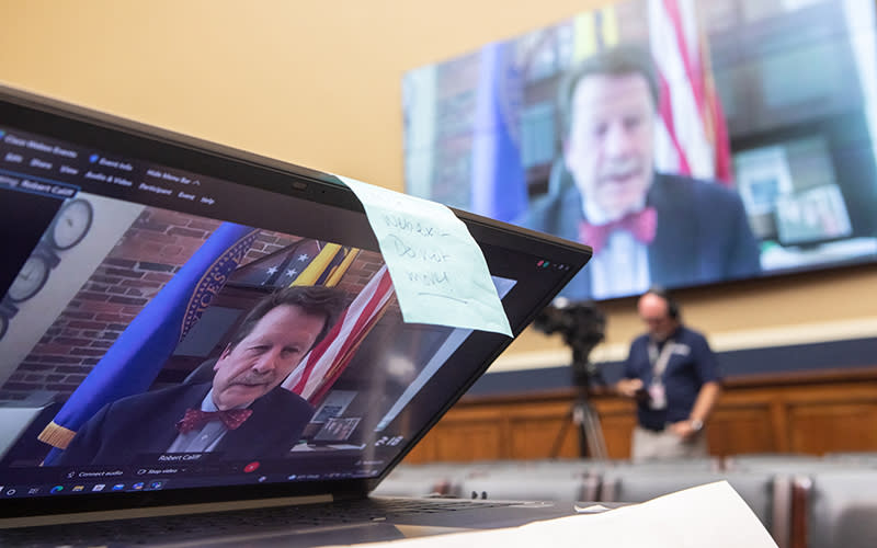 Food and Drug Administration Commissioner Robert Califf virtually delivers his opening statement on a big screen while someone streams from their laptop