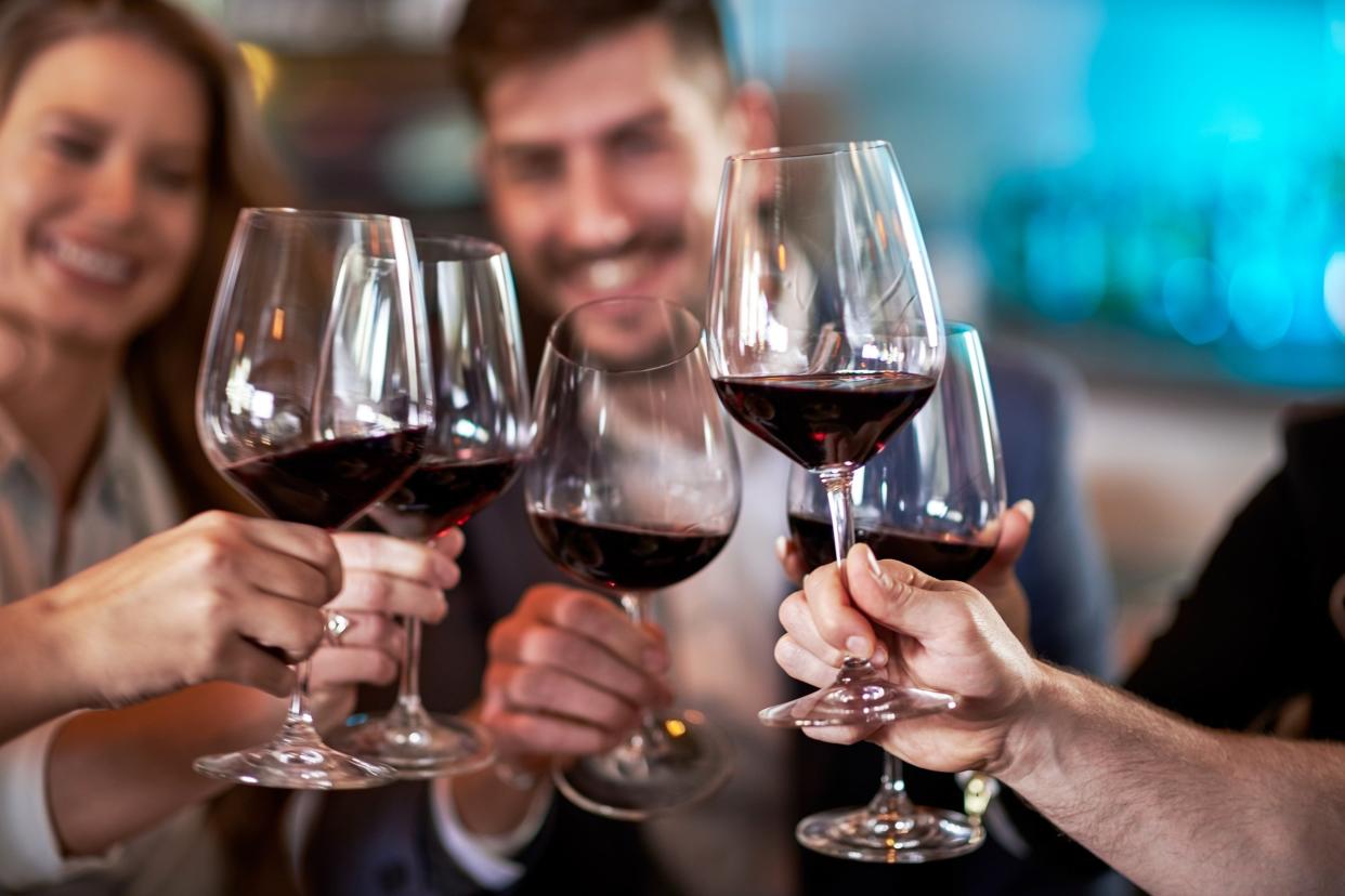 people toasting with red wine in glasses