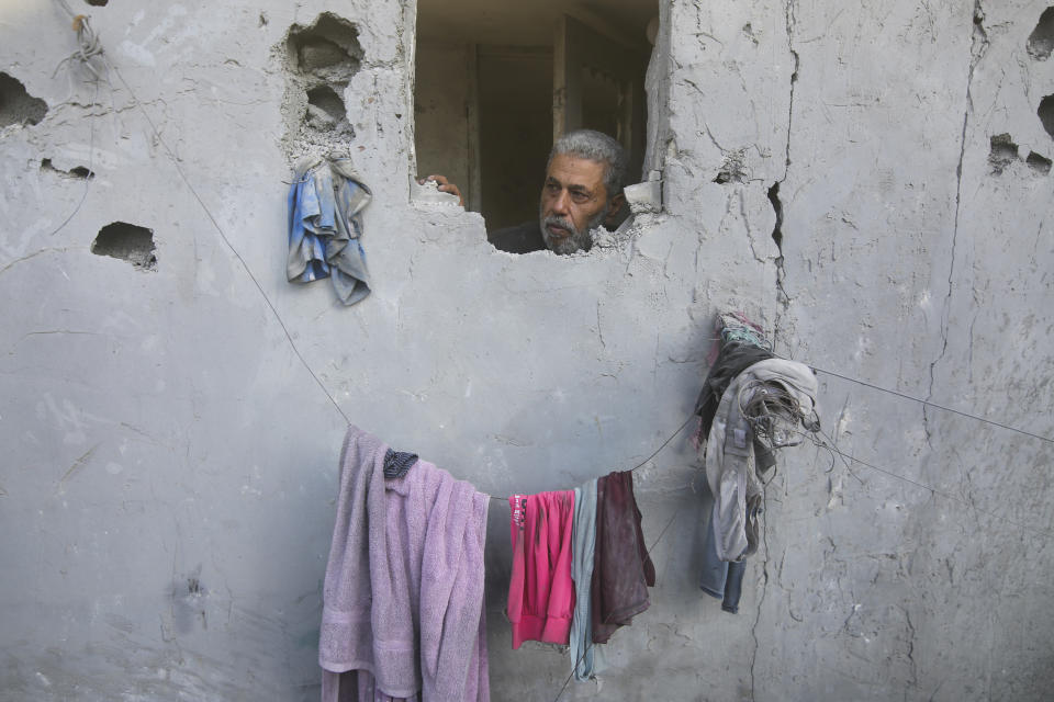 FILE - A Palestinian looks on from his house damaged by Israeli airstrikes in Rafah, southern Gaza Strip, Wednesday, Oct. 18, 2023. Since the Israeli military decided to cut off the Gaza Strip's water and fuel and prevent aid convoys from entering, Palestinians in Gaza have sheltered with their families far from their homes and struggled to survive. It's a grueling routine — waiting hours for bread, trying to find water, soothing children during bombings. (AP Photo/Hatem Ali, File)