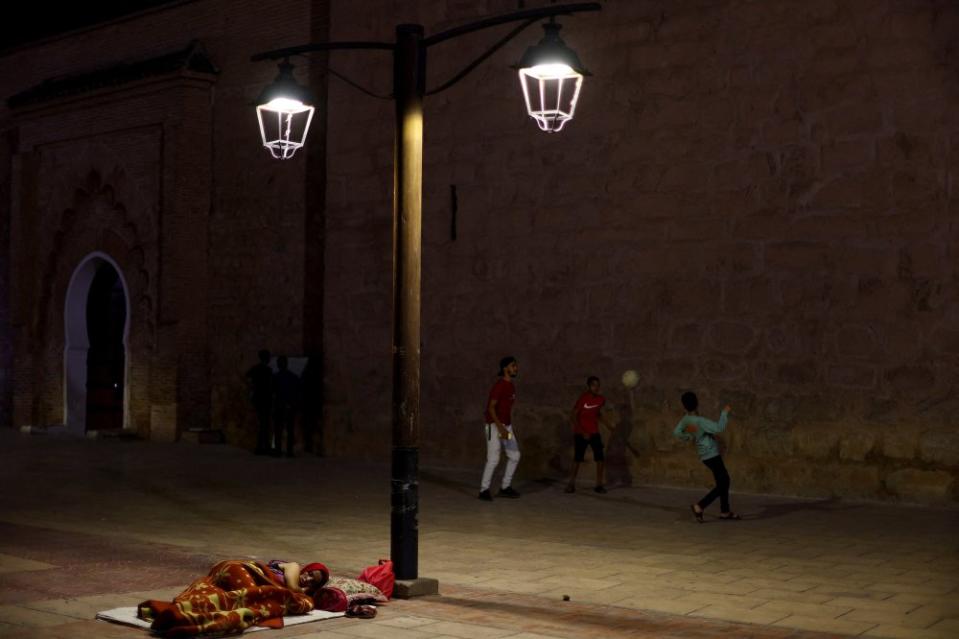 People play soccer next to a woman resting on the sidewalk in Marrakesh, following a powerful earthquake in Morocco, Sept. 9.<span class="copyright">Hannah McKay—Reuters</span>