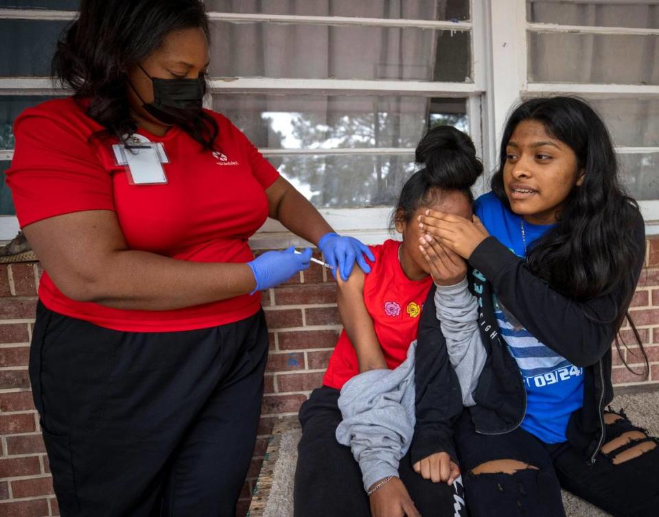 Fifteen-year-old Emily Gutierrez comforts her sister 13-year-old Eily Gutierrez, as Dr. Nerissa Price administers the COVID-19 vaccine on the porch of the family home on Friday, October 8, 2021 in Raleigh, N.C.