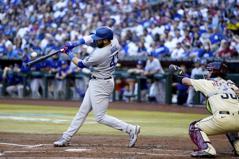 Los Angeles Dodgers' Edwin Rios, left, connects for a three-run home run as Arizona Diamondbacks.