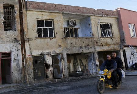 Men drive past a building which was damaged during the security operations and clashes between Turkish security forces and Kurdish militants, in the southeastern town of Silvan in Diyarbakir province, Turkey, December 7, 2015. REUTERS/Murad Sezer