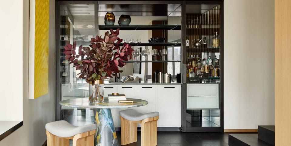 bar area with black flooring and round pedestal table in the corner and a built in bar with mirrored shelving behind it