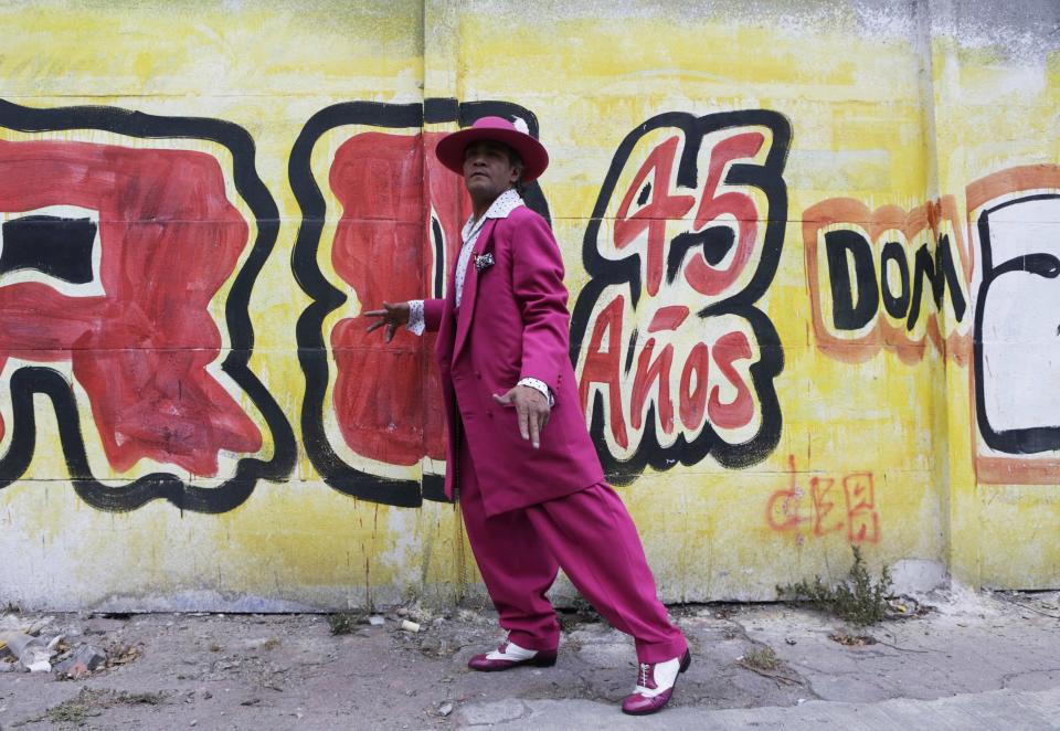 Jesus Gonzalez de la Rosa wears his "Pachuco" outfit while posing for a photograph next to a wall with graffiti in Mexico City