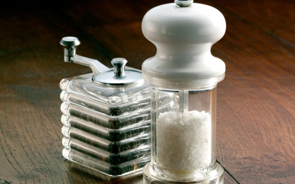 Salt and pepper mills on a wooden table - Alamy