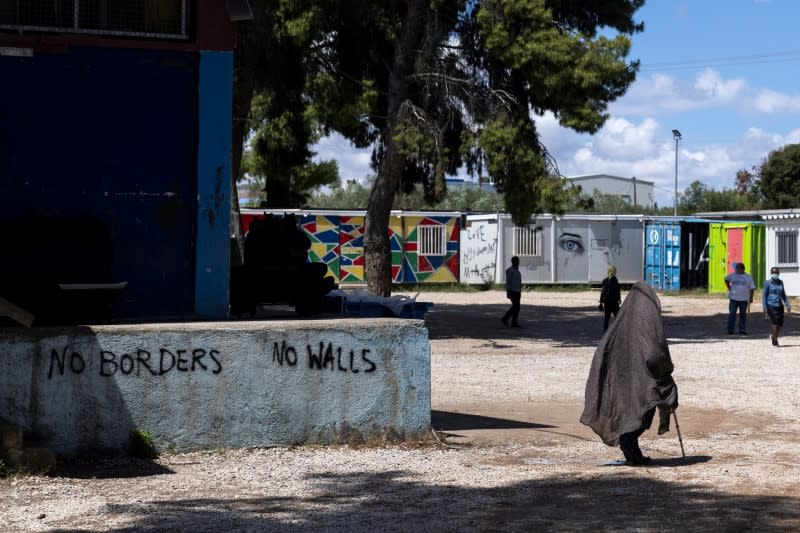 Woman walks past graffiti inside the Ritsona camp for refugees and migrants