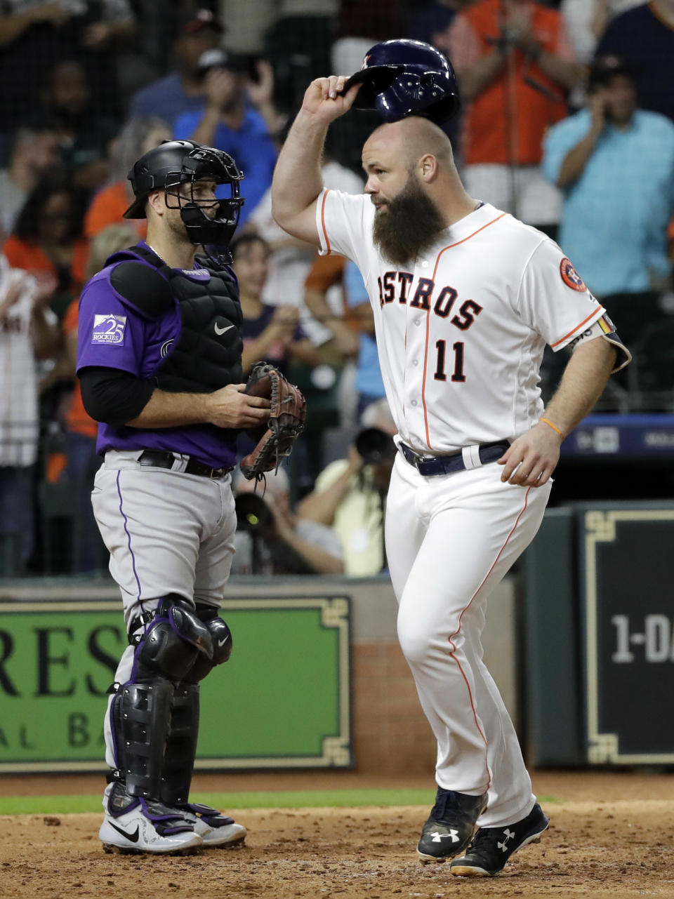 Houston Astros' Evan Gattis (11) celebrates after hitting a home run as Colorado Rockies catcher Chris Iannetta stands near home plate during the fifth inning of a baseball game Wednesday, Aug. 15, 2018, in Houston. (AP Photo/David J. Phillip)