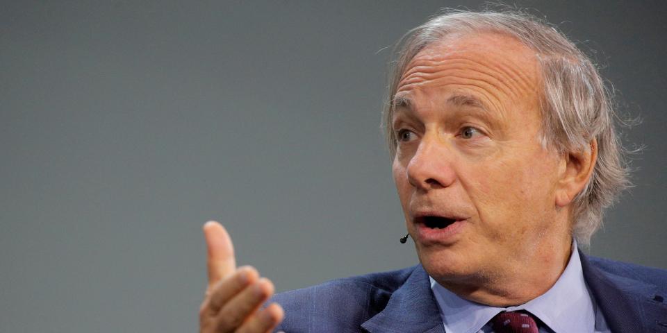 Bridgewater founder Ray Dalio gestures in front of a gray background.