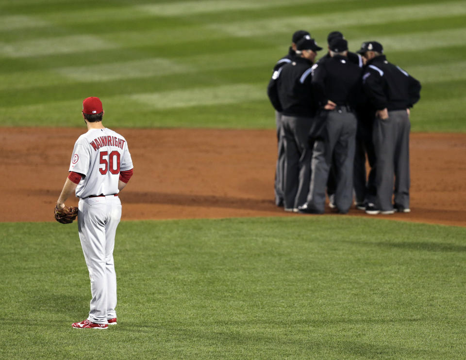 FILE - In this Oct. 23, 2013, file photo, St. Louis Cardinals starting pitcher Adam Wainwright watches as umpires discuss a ruling during the first inning of Game 1 of baseball's World Series against the Boston Red Sox in Boston. Major League Baseball announced Thursday, Jan. 16, 2014, that it will greatly expand instant replay to review close calls starting this season. Each manager will be allowed to challenge at least one call per game. If he's right, he gets another challenge. After the seventh inning, a crew chief can request a review on his own. (AP Photo/Charles Krupa, File)