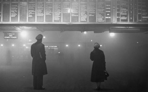  Two passengers looking at the train departure board at Liverpool Street Station, London, during heavy fog, 29th January 1959 - Credit: Edward Miller/Hulton Archive