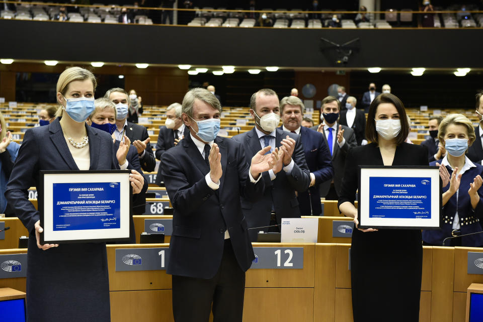 European Parliament President David Sassoli, center, applauds as Belarus opposition leaders Veranika Tsapkala, left, and Svetlana Tikhanovskaya, right, hold their prizes during the Sakharov Prize ceremony at the European Parliament in Brussels, Wednesday, Dec 16, 2020. The European Union has awarded its top human rights prize to the Belarusian democratic opposition. (John Thys/Pool Photo via AP)