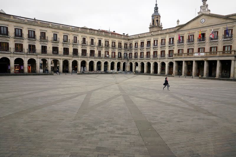 A woman walks across an empty square in the Basque city of Vitoria