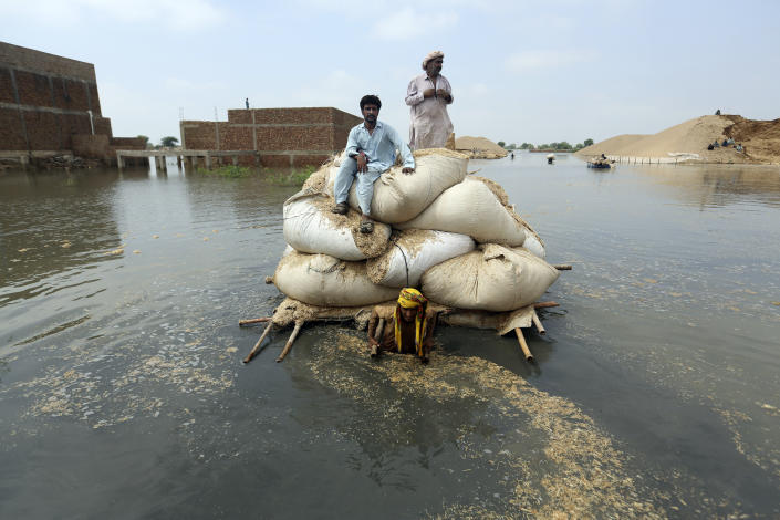 FILE - Victims of the unprecedented flooding from monsoon rains use makeshift barge to carry hay for cattle, in Jaffarabad, a district of Pakistan's southwestern Baluchistan province, Sept. 5, 2022. (AP Photo/Fareed Khan, File)