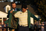 Hideki Matsuyama, of Japan, puts on the champion's green jacket with help from Dustin Johnson after winning the Masters golf tournament on Sunday, April 11, 2021, in Augusta, Ga. (AP Photo/David J. Phillip)