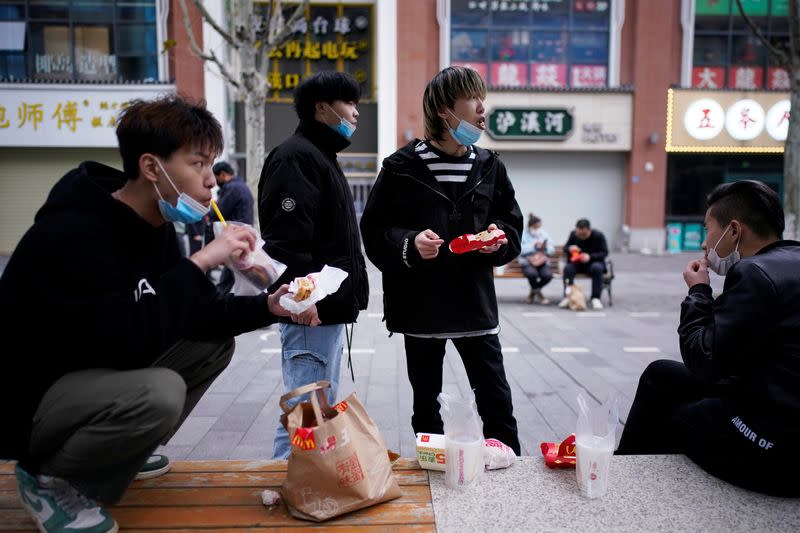 People with face masks eat outside a McDonald's restaurant in Wuhan