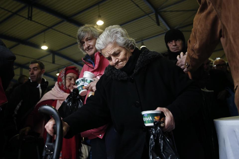 Homeless people hold yogurts as they leave a New Year's meal for the homeless organized by the municipality of Athens, Wednesday, Jan. 1, 2014. Homelessness has increased dramatically during the financial crisis in Greece, which has depended on international rescue loans for more than three years. (AP Photo/Petros Giannakouris)