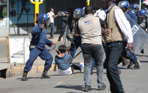 Zimbabwe Republic Police charge protesters in central Harare - Credit: AARON UFUMELI/EPA-EFE/REX