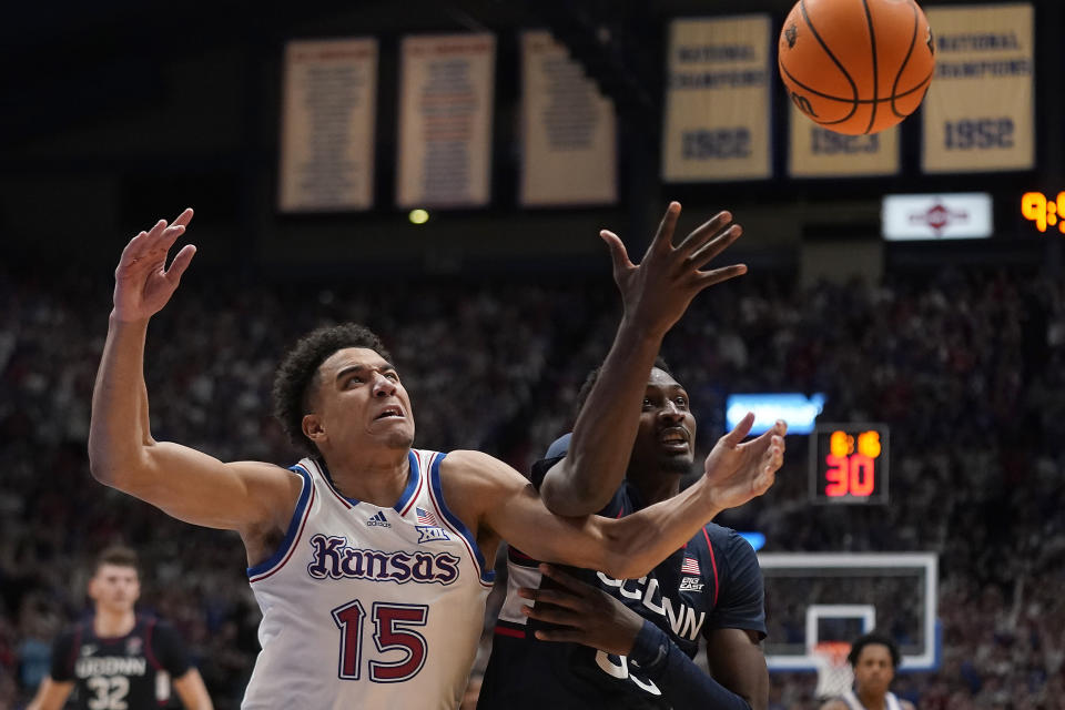 Kansas guard Kevin McCullar Jr. (15) and UConn forward Samson Johnson, right, chase a loose ball during the second half of an NCAA college basketball game Friday, Dec. 1, 2023, in Lawrence, Kan. Kansas won 69-65. (AP Photo/Charlie Riedel)