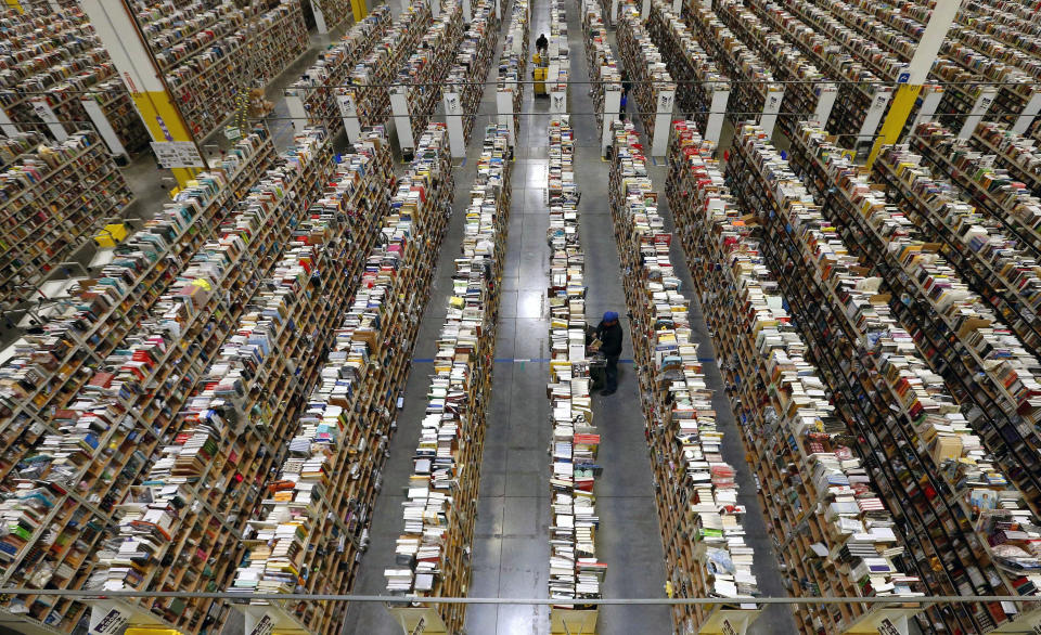 FILE - In this Monday, Dec. 2, 2013, file photo, an Amazon.com employee stocks products along one of the many miles of aisles at an Amazon.com Fulfillment Center in Phoenix. Holiday sales jobs are now likelier to be in warehouses and trucks than in retail stores. Amazon alone planned to hire 20,000 more holiday workers this year, according to the personnel firm Challenger, Gray & Christmas. (AP Photo/Ross D. Franklin, File)