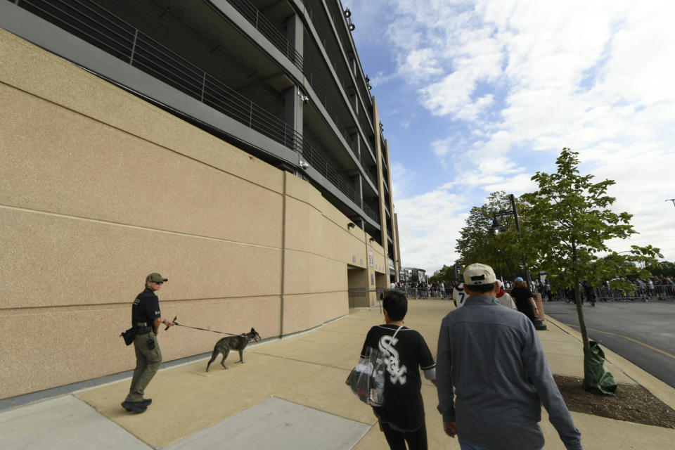 A security guard and dog patrol as fans arrive before a baseball game between the Chicago White Sox and the Oakland Athletics at Guaranteed Rate Field Saturday, Aug. 26, 2023, in Chicago. (AP Photo/Paul Beaty)