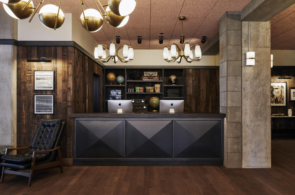 This photo shows the lobby in The Hoxton Hotel in Portland, Ore. London/L.A.-based Fettle designed Portland's Hoxton. Alongside newly-built rooms, public areas were situated in an old converted movie theater. Tailored but comfy mohair and leather seating and warm wood side tables blend with distressed rugs and displays of ceramics, plants and books. Refurbished timber and concrete beams frame the spaces. And there's a great story about the reception area's wood paneling. "We used a lot of local suppliers and material for this project," Parker says. "The area around Portland is a big producer of Maraschino cherries; the visible face of the wall is made from the outside of reclaimed cherry vats. If you look closely you can even see the imprints where the metal belts that hold the huge vats together were pressed against the wood." (Ennismore/The Hoxton via AP)