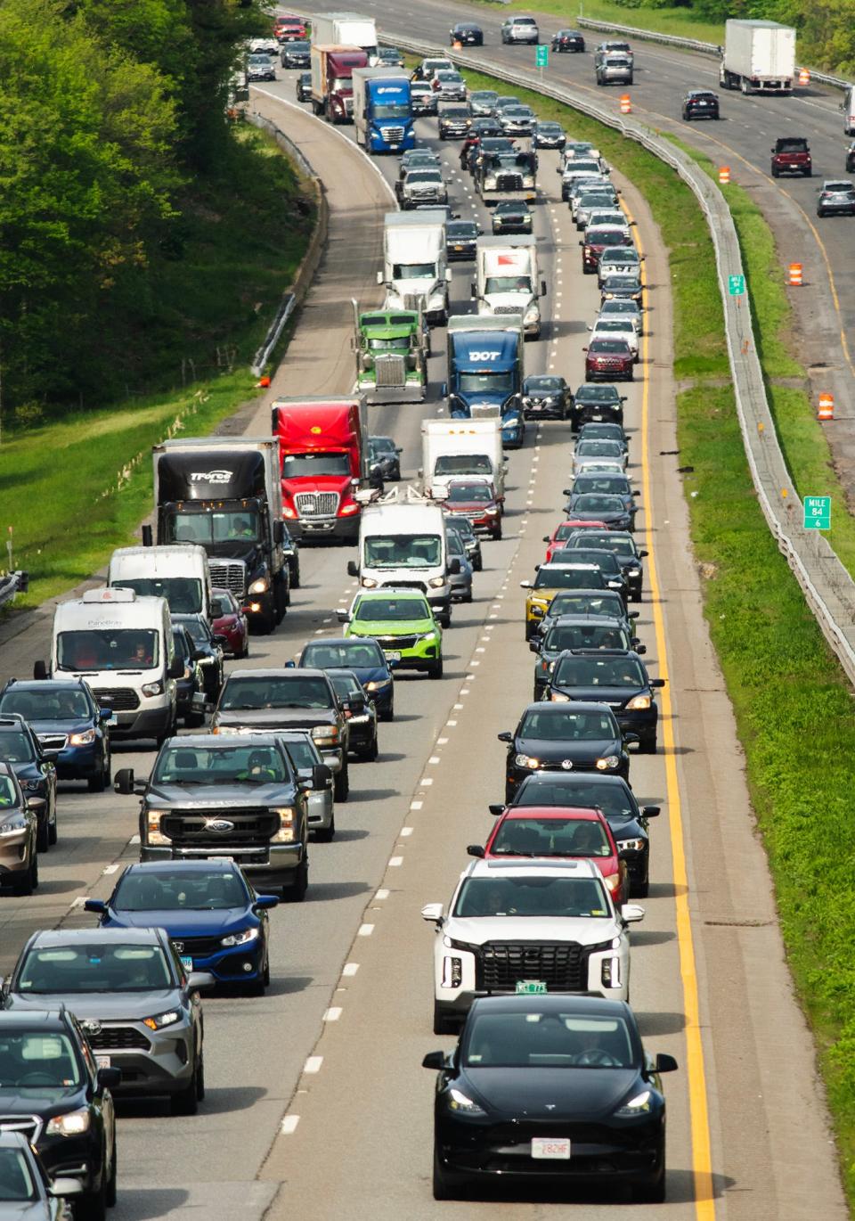 Westbound traffic on the Mass Pike slowly approaches the scene of a hazardous materials leak on the eastbound side in Charlton Monday.