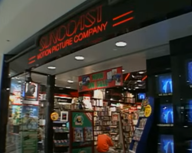 Front view of a Suncoast Motion Picture Company store entrance with visible signage and display of DVDs