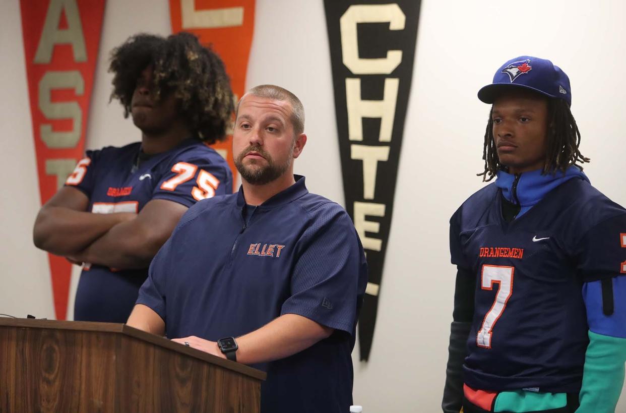 Ellet High School head football coach Steve Fasig, center, speaks during the Akron Public Schools Football Media Day as he stands between players Ramon McAndrews, left, and Tim Peake. Fasig has been placed on leave following the death of a player after a recent outing.