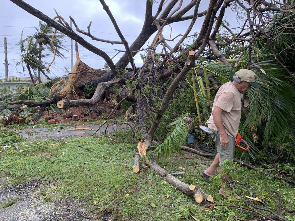 Andy Villagomez clears what remains of a large tree that overshadowed his front yard before falling to Typhoon Mawar, Thursday, May 25, 2023, in Mongmong-Toto-Maite, Guam. (AP Photo/Grace Garces Bordallo)