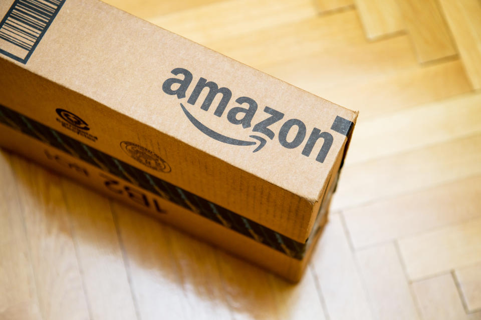 Paris, France - January 28, 2016: Amazon logotype printed on cardboard box side seen from above on a wooden parwuet floor. Amazon is an American electronic e-commerce company distribution worlwide e-commerce goods