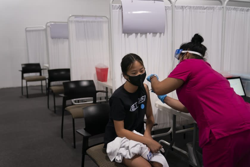 Melody Chuang, 14, receives her first dose of the Pfizer COVID-19 vaccine at a vaccination site in Santa Ana.