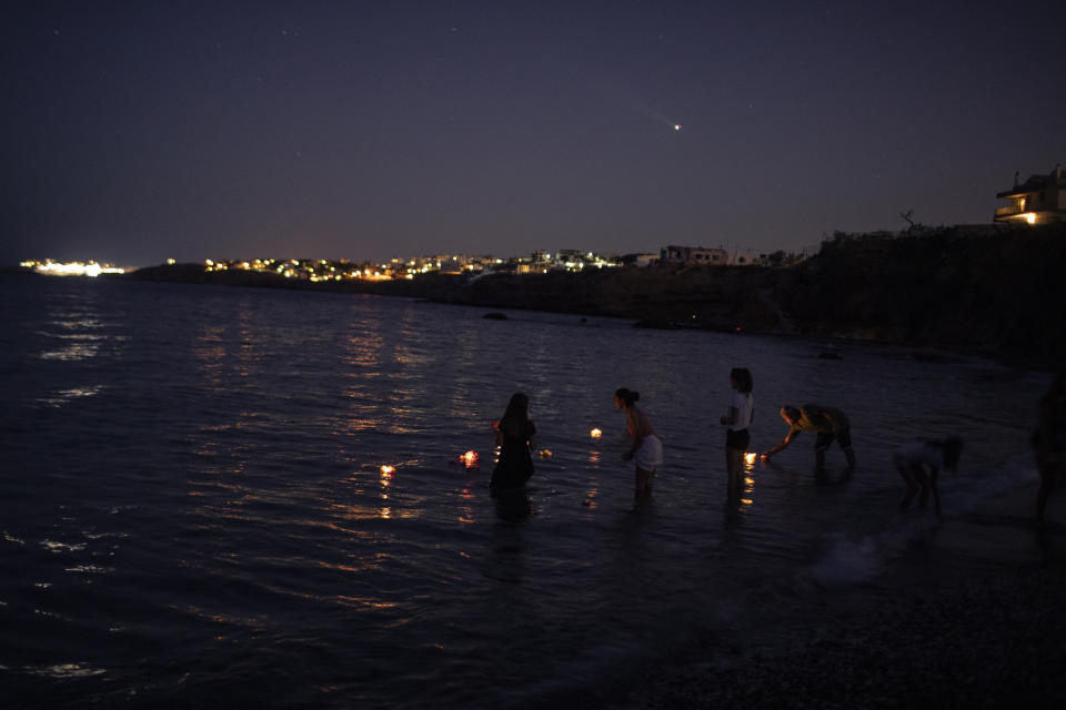 People place candles and flowers into the sea in Mati near Athens, on Tuesday, July 23, 2919, in the memory of the victims of a fire at a beach. A year ago Tuesday, a wildfire gutted the nearby resort of Mati and other seaside areas, destroying more than a thousand homes and killed over 100 people. (AP Photo/Petros Giannakouris)