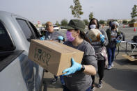 Volunteers load a pickup truck at a food distribution center set up at SoFi Stadium ahead of Thanksgiving and amid the COVID-19 pandemic, Monday, Nov. 23, 2020, in Inglewood, Calif. (AP Photo/Marcio Jose Sanchez)