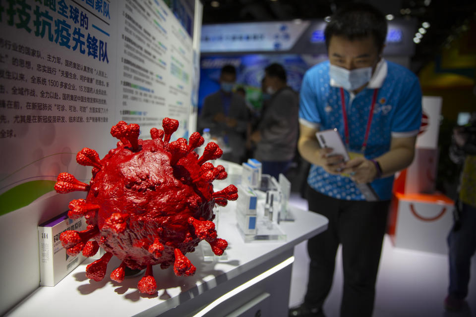 A visitor wearing a face mask takes a photo of a model of a coronavirus and boxes for COVID-19 vaccines at a display by Chinese pharmaceutical firm Sinopharm at the China International Fair for Trade in Services (CIFTIS) in Beijing, Saturday, Sept. 5, 2020. With the COVID-19 pandemic largely under control, China's capital on Saturday kicked off one of the first large-scale public events since the start of the coronavirus outbreak, as tens of thousands of attendees were expected to visit displays from nearly 2,000 Chinese and foreign companies showcasing their products and services. (AP Photo/Mark Schiefelbein)