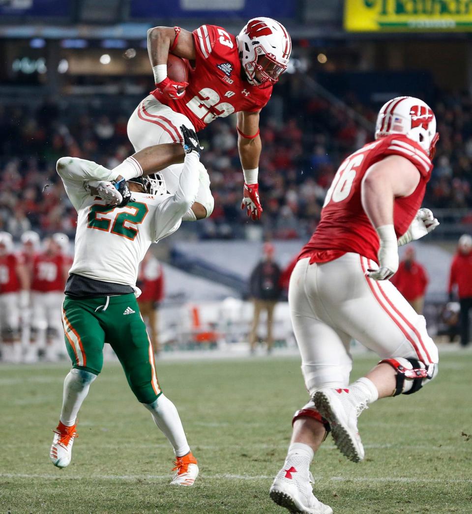 Wisconsin running back Jonathan Taylor tries to hurdle Miami defensive back Sheldrick Redwine during the Pinstripe Bowl. Taylor rushed for 205 yards in the game.