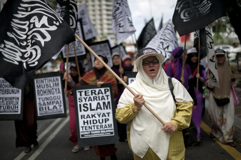 Malaysian Muslim activists carry flags and banners during a peaceful protest against the persecution of Rohingya Muslims in Myanmar, outside the Myanmar embassy in Kuala Lumpur, on February 14, 2014