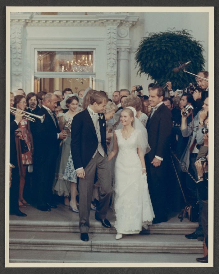 In this photograph, a beaming Tricia Nixon looks up at her new husband Edward Cox outside the North Door to the White House as her father, President Richard M. Nixon, looks on.