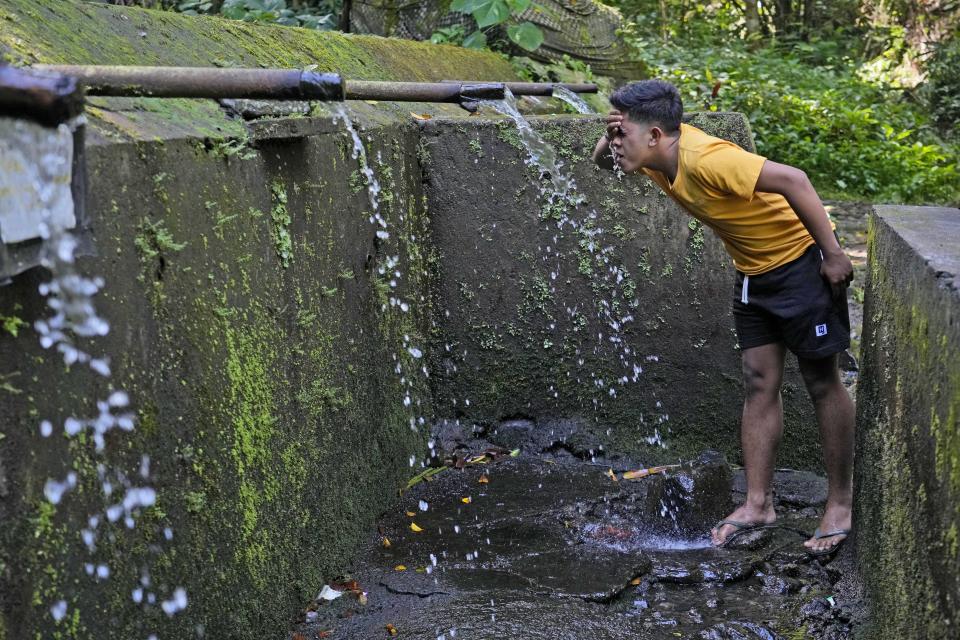 A man washes his face from water in Munduk, Bali, Indonesia, Sunday, April 17, 2022. In less than a decade, Bali's water table has decreased over 50 meters (164 feet) in some areas, raising concerns that it could lead to worsening water crisis on the tropical tourist destination. (AP Photo/Tatan Syuflana)