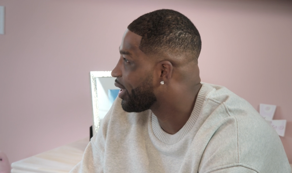 Tristan Thompson wears a casual grey sweater and sits indoors, facing left and speaking