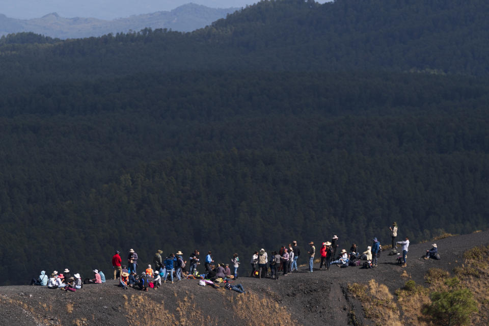 Un grupo de personas que forman parte de un congreso internacional de vulcanología descansa en el borde del cráter del volcán Paricutín, en Mexico, el miércoles 22 de febrero de 2023. El cráter del volcán mide unos 200 metros y es posible subir a la cima del volcán, así como caminar por el perímetro entero. (AP Foto/Eduardo Verdugo)