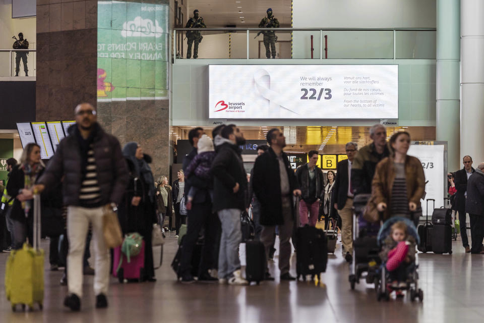 Soldiers patrol as passengers walk through the departure terminal, marking the one-year anniversary at Zaventem Airport in Brussels on Wednesday, March 22, 2017. The suicide bombings at the Brussels airport and subway on March 22, 2016, killed 32 people and wounded more than 300 others. (AP Photo/Geert Vanden Wijngaert)