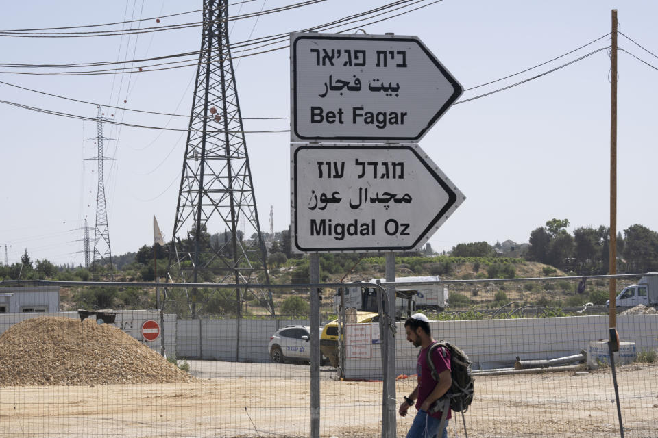 An Israeli settler walks to a bus stop at the Gush Etzion junction, the transportation hub for a number of West Bank Jewish settlements, Thursday, June 9, 2022. Israeli settlers in the occupied West Bank may soon have a taste of the military rule that Palestinians have been living under for 55 years. A looming end-of-month deadline to extend legal protections to Jewish settlers has put Israel’s government on the brink of collapse and drawn widespread warnings that the territory could be plunged into chaos. (AP Photo/Maya Alleruzzo)