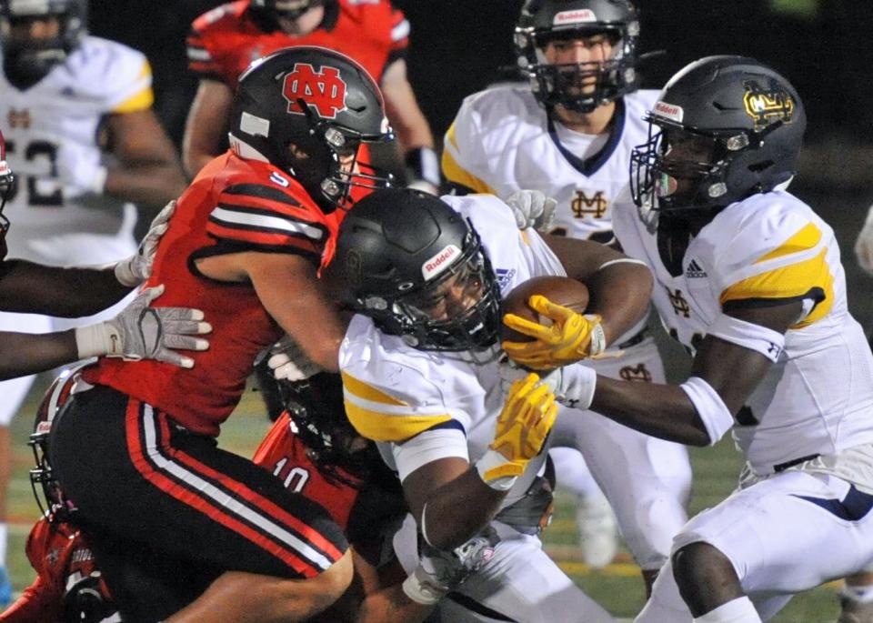 North Quincy's Nate Caldwell, left, takes down Malden Catholic's Marcus Rojas, center, during high school football action at Veterans Memorial Stadium in Quincy, Friday, Sept. 23, 2022.