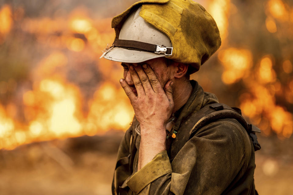 Firefighter Matthew Gerzin of Alaska's Pioneer Peak Interagency Hotshot crew rubs his eye while battling the Mosquito Fire in the Volcanoville community of El Dorado County, Calif., on Friday, Sept. 9, 2022. (AP Photo/Noah Berger)