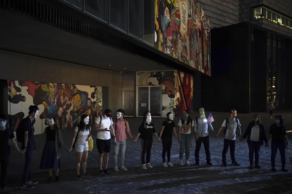 Protesters wear mask and link their hands forming a human chain during a protest in Hong Kong, Friday, Oct. 18, 2019. Hong Kong pro-democracy protesters are donning cartoon/superheroes masks as they formed a human chain across the semiautonomous Chinese city, in defiance of a government ban on face coverings. (AP Photo/Felipe Dana)